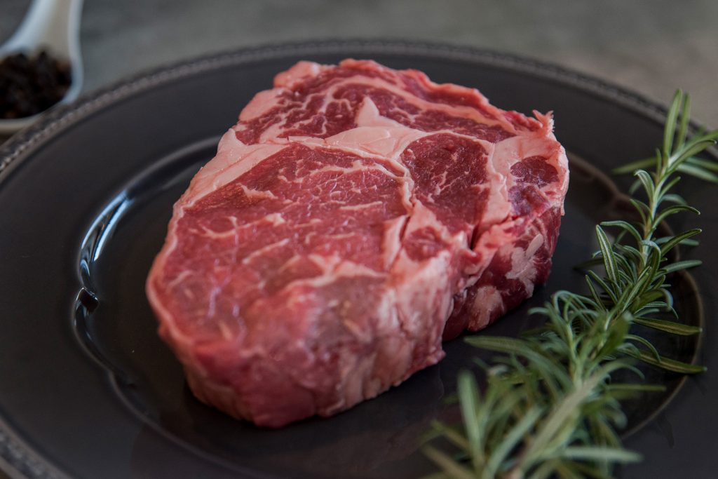 Baby Beef García crudo en plato oscuro con romero, corte premium de parrilla en Montevideo
