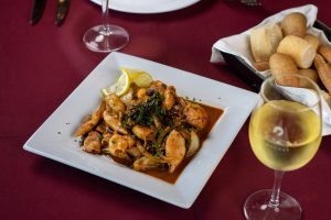 Salteado de camarones y txipirones en salsa, servido en plato cuadrado en García Uruguay.