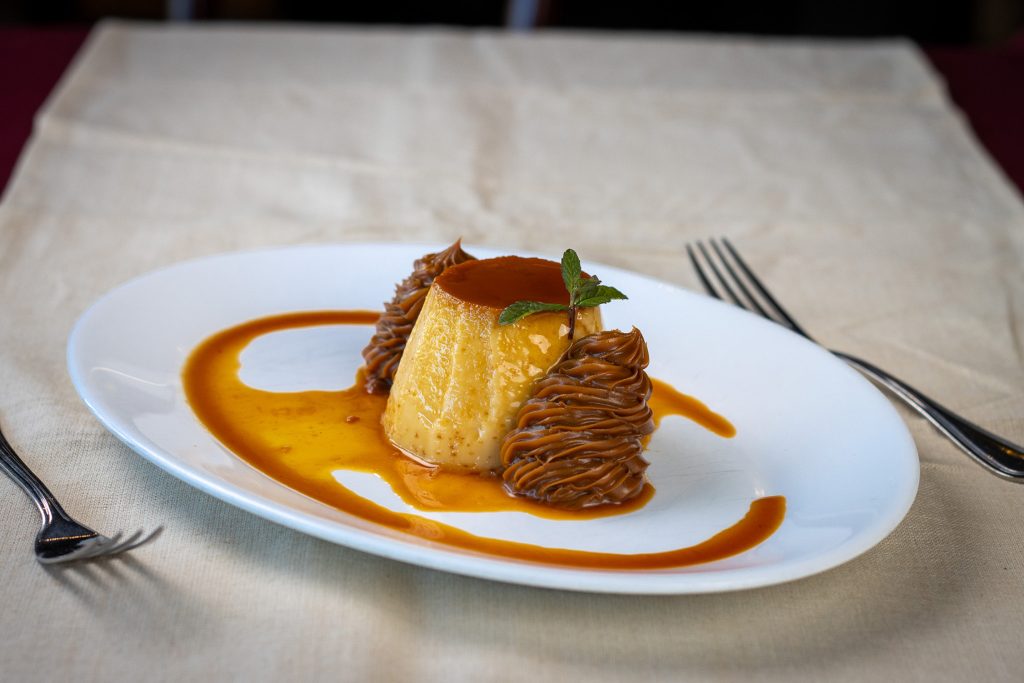 Flan casero con dulce de leche y salsa de caramelo, servido en plato ovalado en García Uruguay.