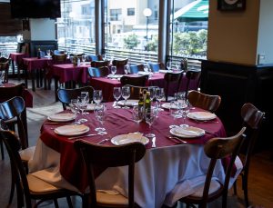 Salón de García con mesas redondas vestidas en mantel bordó y cristalería