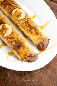 Panqueques rellenos de dulce de leche con salsa de caramelo, servidos en plato blanco en García Uruguay.